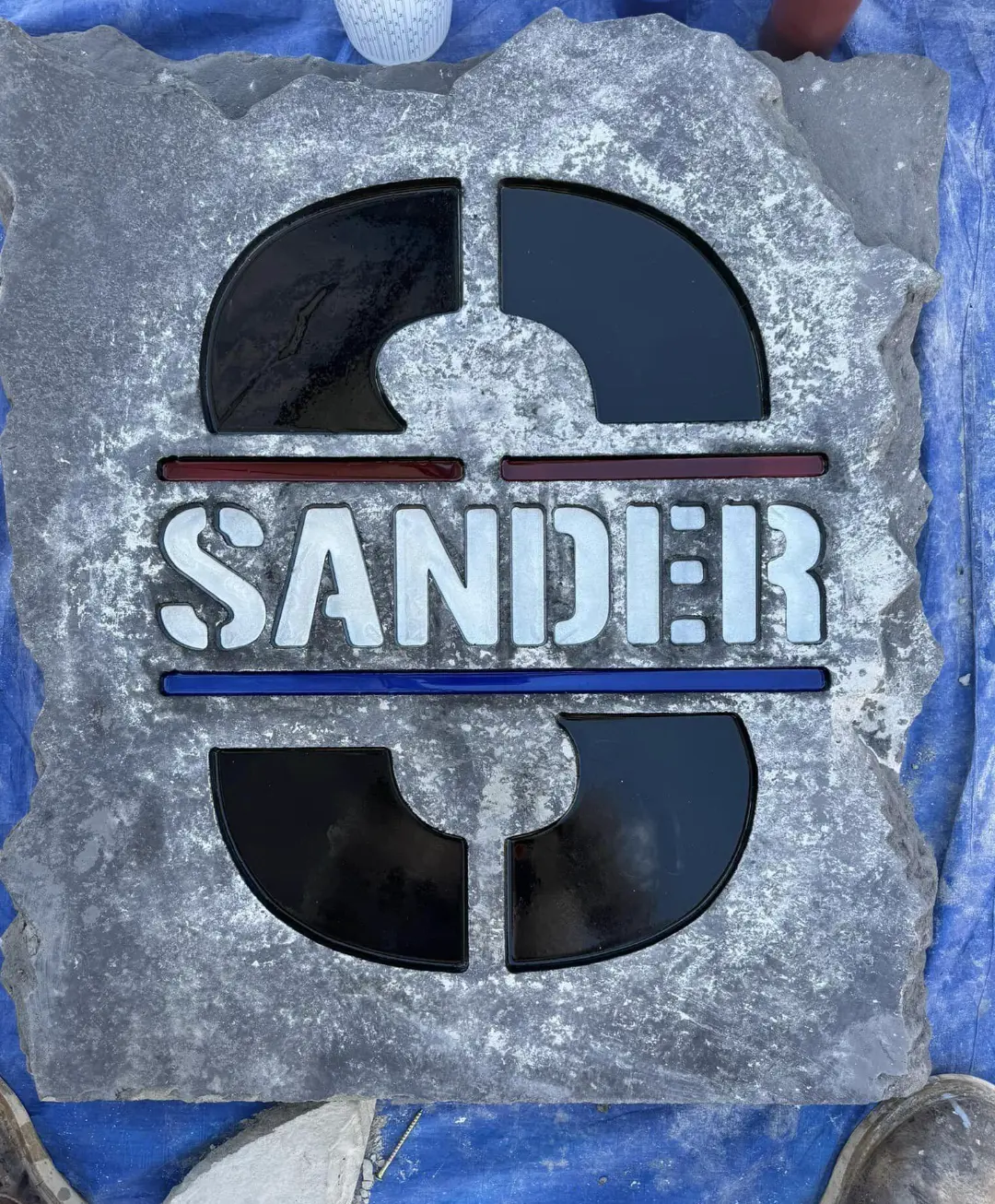 Sander logo engraved and inlaid with color on a stone panel